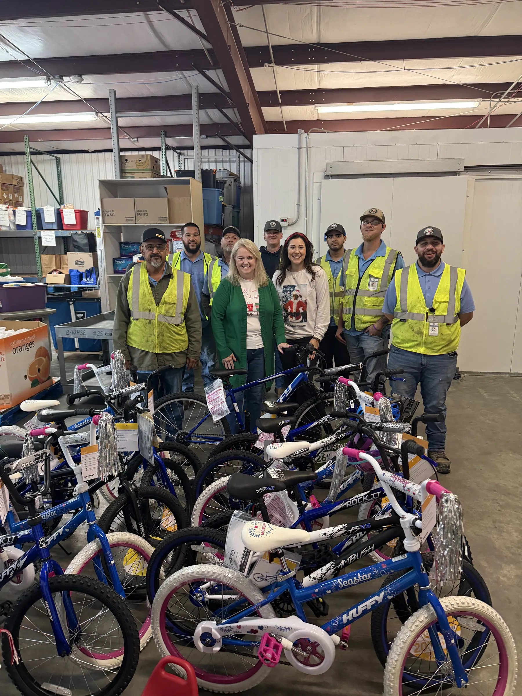 Volunteers stand with rows of bicycles donated for the holidays.