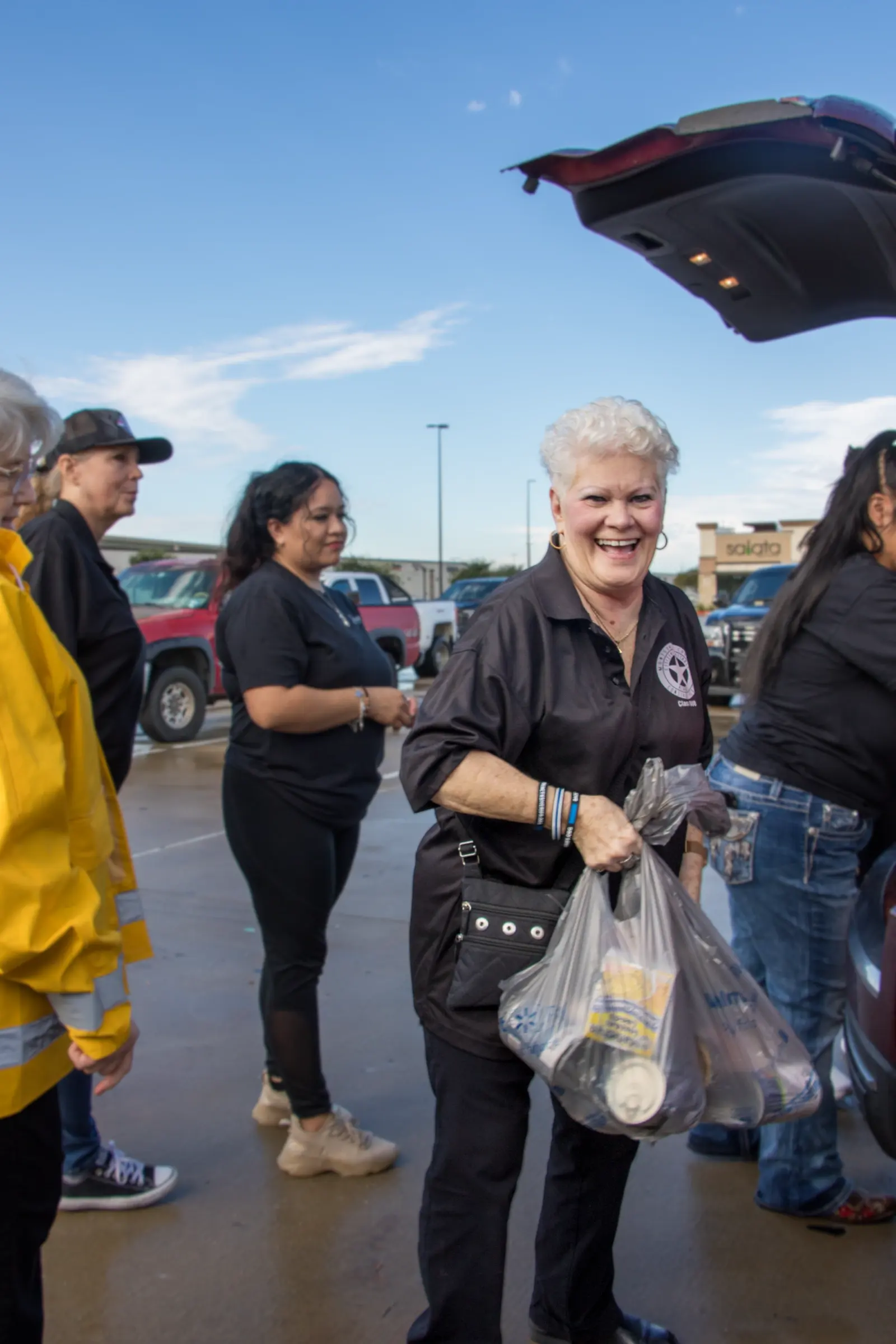 A volunteer holds grocery bags in a parking-lot distribution.
