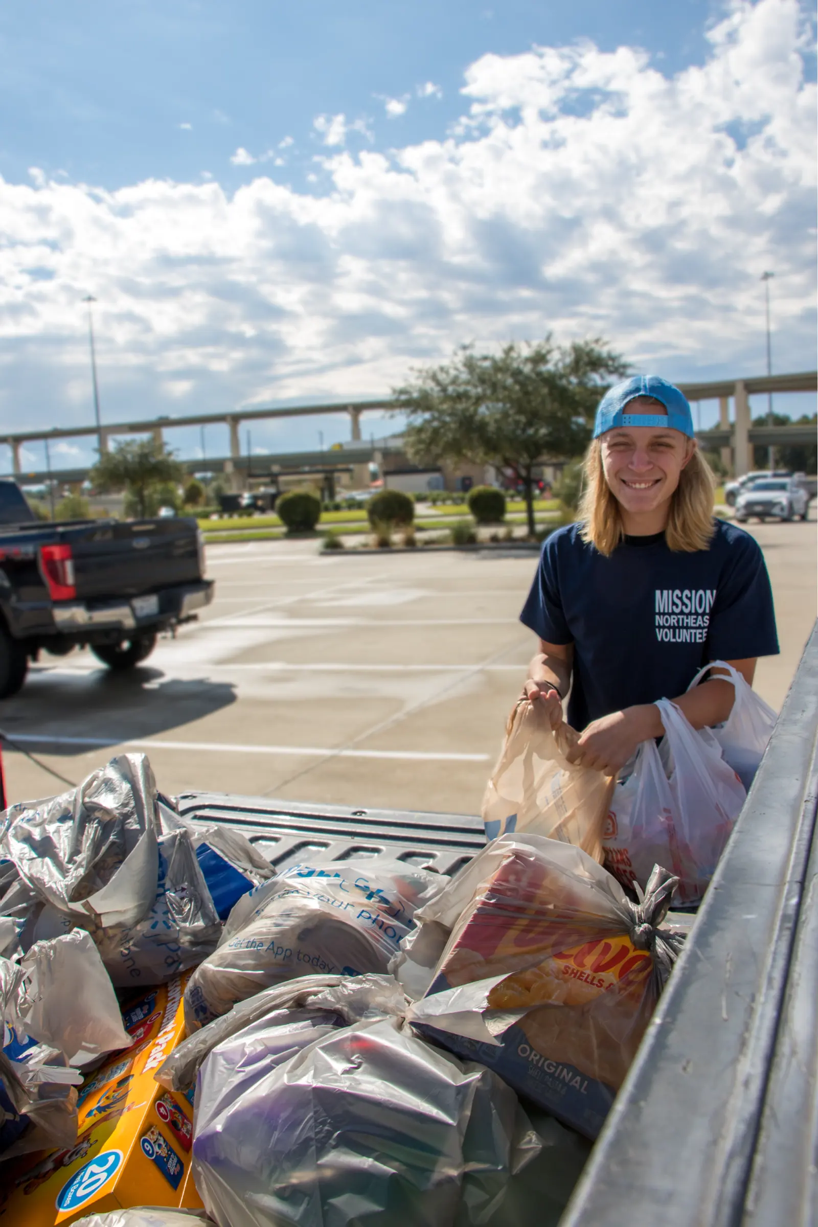 A volunteer sorts grocery bags in the bed of a pickup.